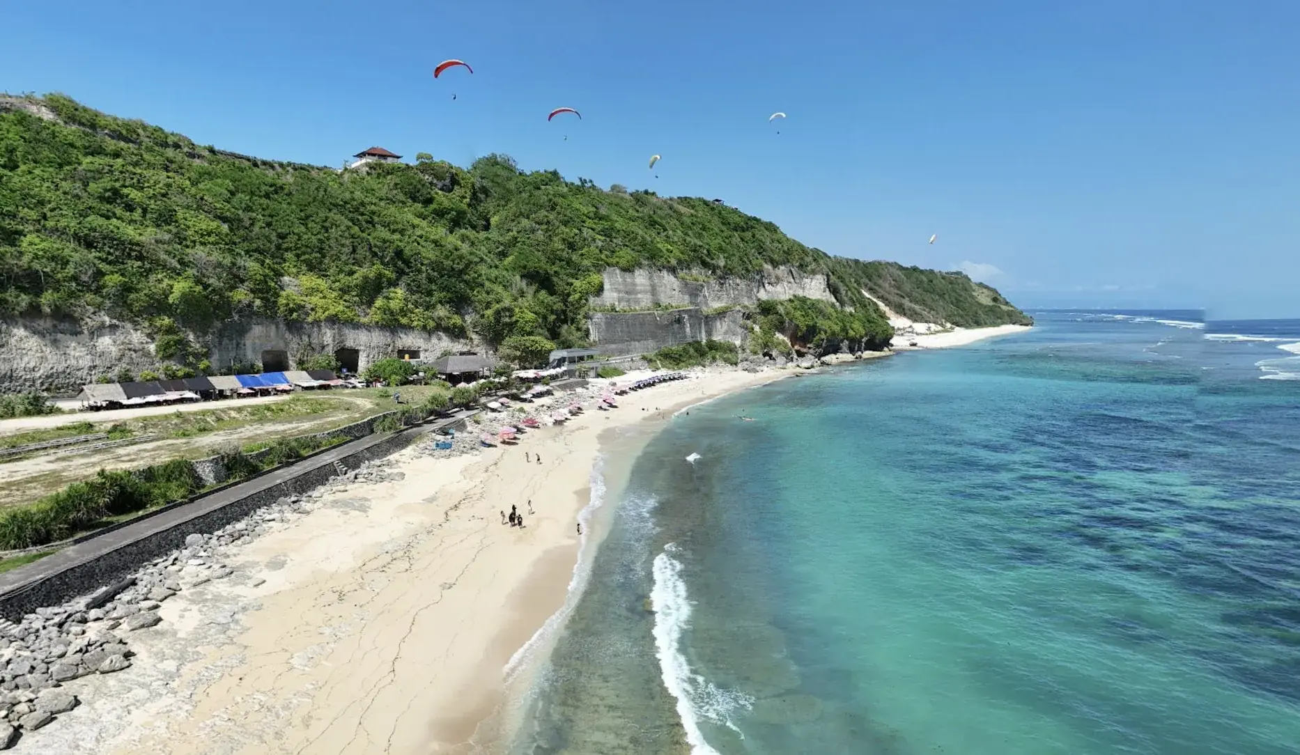 Pandawa Beach from above, with paragliders over the white cliffs.