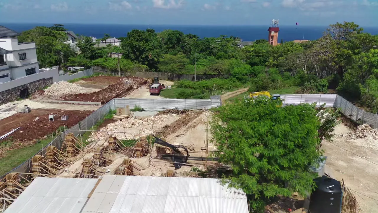 The Royale site from a drone: cleared plots, foundations in progress, the ocean beyond. Photograph.